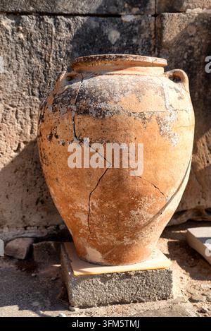 Primo piano di un grande vaso di stoccaggio in ceramica antica con crepe visibili e superficie erosa nel sito archeologico di Phaistos a Creta, Grecia, ripres Foto Stock