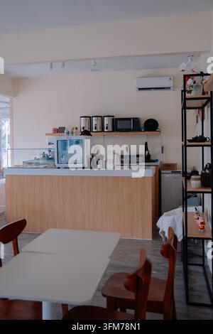 Interno di un caffè minimalista moderno che mostra il bancone degli ordini e l'area seduta in legno Foto Stock