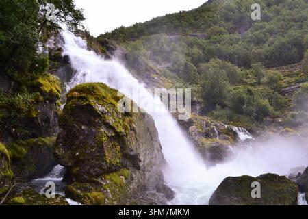 Potente cascata che si riversa su rocce ricoperte di muschio in Norvegia Foto Stock