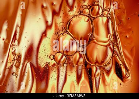 Sfondo astratto liquido dorato con bolle di olio e gocce d'acqua che creano texture e motivi intricati Foto Stock
