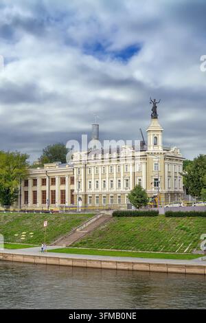 Argini del fiume Vilia a Vilnius, Lituania, vista con casa torre storica. Scultura con lanterna Foto Stock