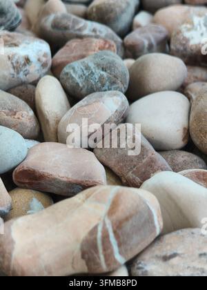 Prima vista di varie pietre di fiume lisce nei toni terrosi naturali disposte armoniosamente Foto Stock