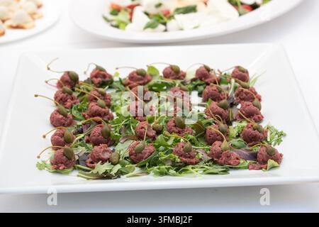 Mini porzioni di tartara di manzo con bacche di capperi e verdure miste su un vassoio da catering Foto Stock
