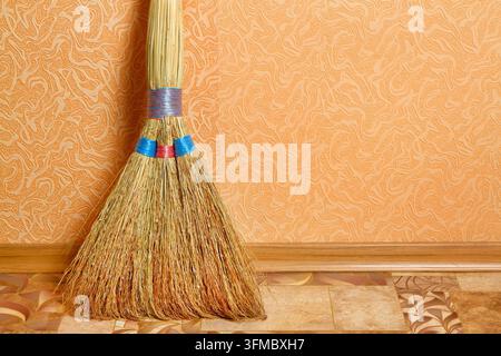Scopa per spazzare nella stanza contro il muro. Primo piano della scopa. Foto Stock