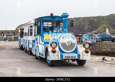 Stonehaven, Scozia, UK – 17 agosto 2025: Il treno turistico Stoney Express percorre il lungomare vicino al porto di Stonehaven, trasportando visitatori Foto Stock