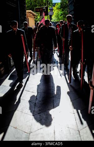 I partecipanti della Processione del Corpus Domini proiettano ombre intense dal sole mattutino mentre entrano nella Chiesa del Sagrario a Siviglia, Andalusia, Spagna. Foto Stock