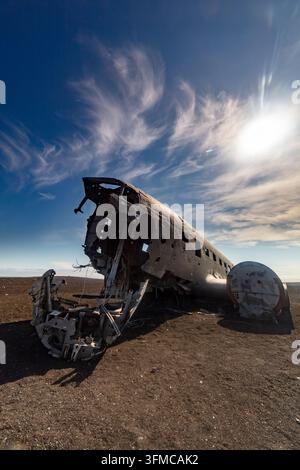 Relitto di aereo arrugginito abbandonato si trova su una pianura desertica desolata sotto un drammatico cielo blu con sottili nuvole bianche. Foto Stock