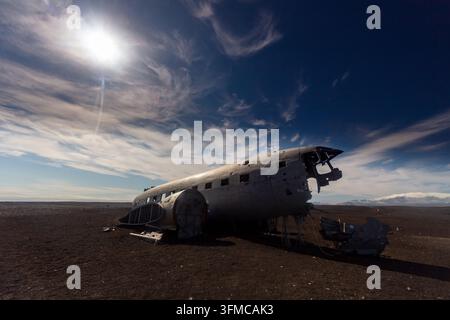 Relitto di aereo arrugginito abbandonato si trova su una pianura desertica desolata sotto un drammatico cielo blu con sottili nuvole bianche. Foto Stock