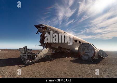 Relitto di aereo arrugginito abbandonato si trova su una pianura desertica desolata sotto un drammatico cielo blu con sottili nuvole bianche. Foto Stock