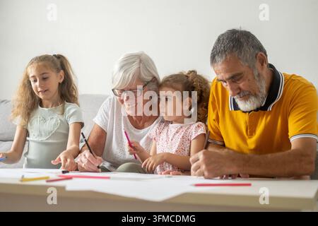 Famiglia multigenerazionale che disegna e colora insieme a casa Foto Stock