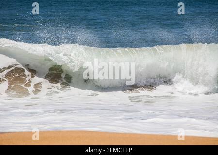 Potente onda dell'oceano si infrange su una spiaggia sabbiosa Foto Stock