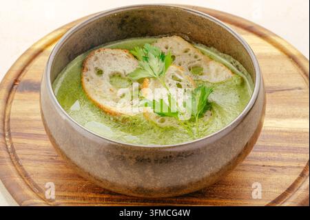 Ciotola di zuppa di crema di verdure verdi con pane e prezzemolo Foto Stock