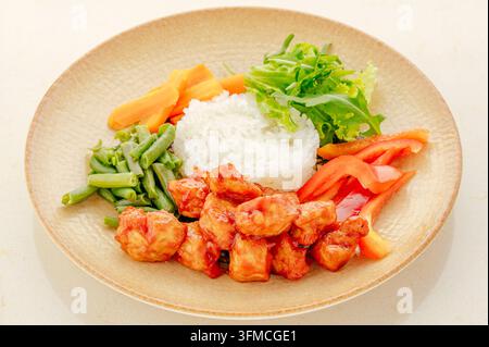 Pollo dolce e aspro con riso e verdure fresche su un piatto Foto Stock