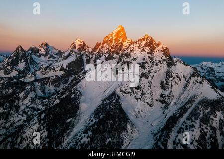Caldo bagliore alpino illumina la vetta di una montagna innevata. Foto Stock