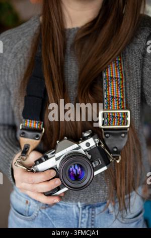 Donna dai capelli lunghi che tiene una macchina fotografica vintage Foto Stock