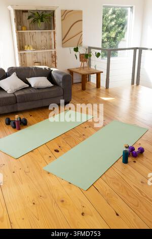 Due stivali da yoga verde menta sono distesi parallelamente su un pavimento di legno verniciato vicino a manubri, bottiglie d'acqua Foto Stock