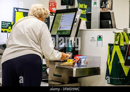 Londra, Regno Unito, 27 settembre 2026, Donna anziana irriconoscibile mentre fa la spesa utilizzando un sistema di autoscansione in un supermercato del Regno Unito Foto Stock