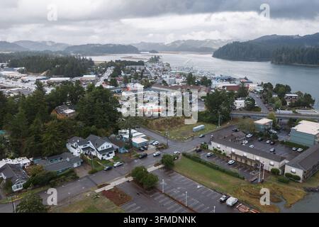 Vista aerea di Florence, Oregon, che mostra la città costiera, i quartieri boscosi, gli edifici commerciali e l'estuario del fiume Siuslaw sotto un sovrappasso Foto Stock