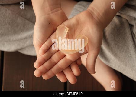 Il bambino tiene un paradenti trasparente in mano, vista ravvicinata dall'alto. Allineatore orale per la correzione di morso, denti e mascella. Ortodontico Foto Stock