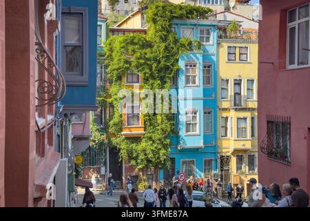 Istanbul, Turchia – 8 ottobre 2025: Folla su una strada acciottolata a Balat con case storiche colorate e una facciata ricoperta di edera Foto Stock