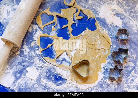 Impasto arrotolato per biscotti al burro con tagliabiscotti e rotolo di torta su base in silicone blu Foto Stock
