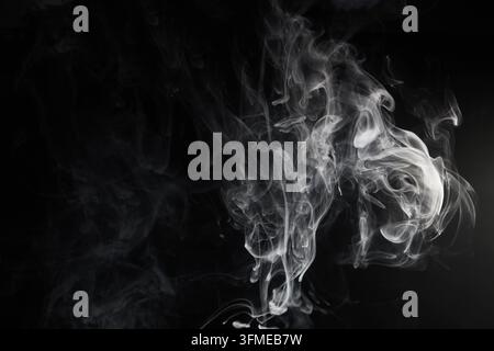 Fumo bianco che crea forme astratte su sfondo nero Foto Stock
