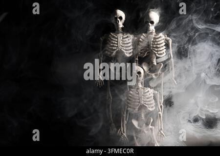 Scheletri che emergono da una spessa fumata bianca su sfondo nero Foto Stock