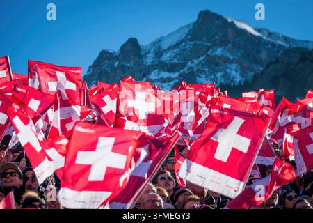 Adelboden, Svizzera - 7 gennaio 2023: Un mare di bandiere che sventolano per mostrare il sostegno svizzero da parte di migliaia di tifosi alla Coppa del Mondo di sci alpino davanti alla montagna innevata Foto Stock