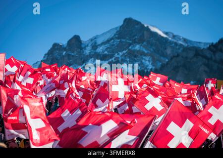 Adelboden, Svizzera - 7 gennaio 2023: Un mare di bandiere che sventolano per mostrare il sostegno svizzero da parte di migliaia di tifosi alla Coppa del Mondo di sci alpino davanti alla montagna innevata Foto Stock