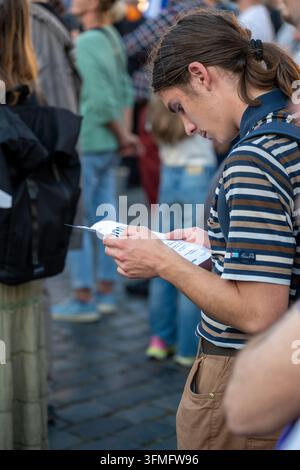 Un partecipante a una manifestazione legge materiale stampato durante un evento Million Moments for Democracy che incoraggia la partecipazione elettorale. Praga, Repubblica Ceca Foto Stock