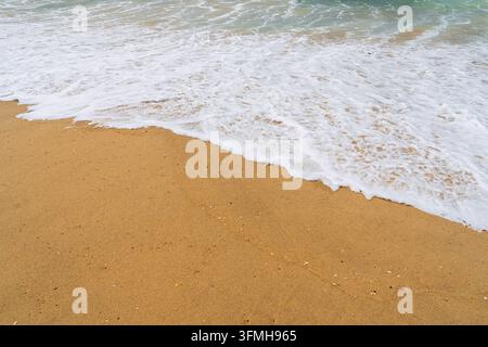 Vista ad angolo alto delle dolci onde dell'oceano che si infrangono su una sabbia dorata di una spiaggia francese soleggiata, catturando il ritmo pacifico della marea e la serenità, luminosa Foto Stock
