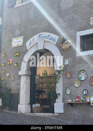 Antico ingresso ad arco del negozio decorato con piatti in ceramica dipinti a mano a Limone sul Garda, Italia Foto Stock