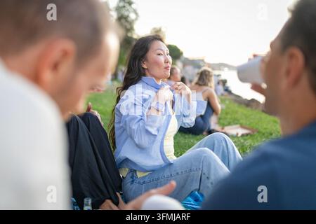 Giovane donna che si gode un picnic con gli amici all'aperto Foto Stock