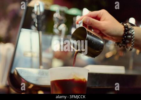 Barista che versa un colpo di espresso fresco in una tazza di caffè freddo in un caffè Foto Stock