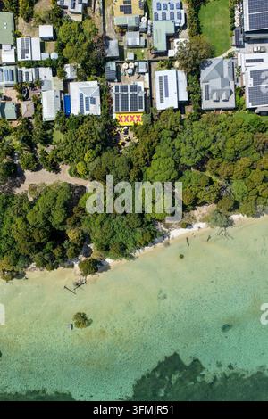 Vista aerea di Moreton Island che mostra l'insediamento costiero di Kooringal con case, alberi rigogliosi e acqua turchese chiara lungo la spiaggia sabbiosa in Foto Stock