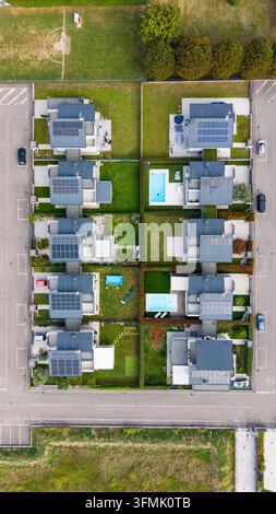 Vista aerea di case residenziali moderne con pannelli solari sui tetti, piscine private e prati verdi in un quartiere suburbano a Mil Foto Stock