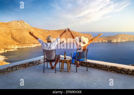 Una coppia di vacanzieri felici si gode il bellissimo tramonto estivo nel mar Mediterraneo dalla propria terrazza con un bicchiere di vino Foto Stock