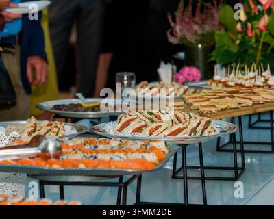 Varietà di sandwich alle dita e antipasti serviti su vassoi durante un evento. Foto Stock