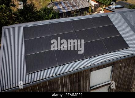 Vista aerea ravvicinata di un impianto di pannelli solari installato sul tetto di una moderna conversione di fienile rivestita in legno. Foto Stock