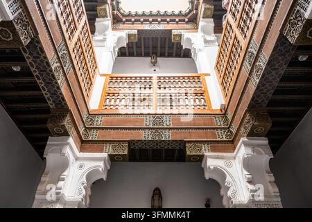 La madrasa Ben Youssef mostra camere per studenti con architettura tradizionale. La vista si dirige verso l'alto delle ringhiere in legno e delle pareti decorative. Lo spazio storico fa parte della cultura dell'apprendimento marocchina. Foto Stock