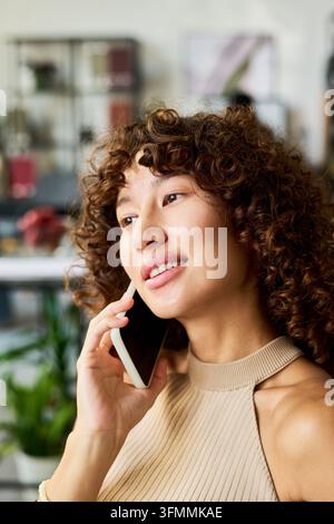 Donna biracial che parla al smartphone in uno studio creativo Foto Stock