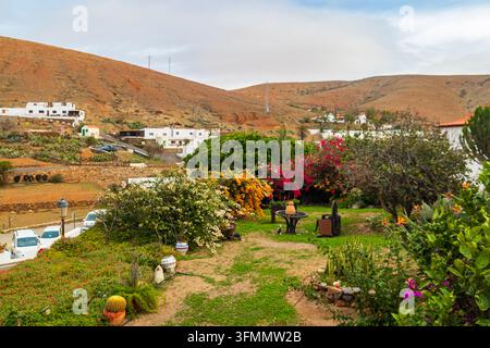Vista panoramica della storica città di Betancuria con i suoi edifici bianchi tradizionali, palme verdi e un bellissimo giardino con bougainvillea in fiore Foto Stock