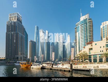 Grattacieli moderni e barche di lusso ormeggiate lungo il canale lungo la costa a Dubai Marina, Dubai, Emirati Arabi Uniti Foto Stock