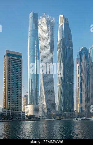 Torre Cayan contorta e grattacieli futuristici che si riflettono sull'acqua del canale a Dubai Marina, Dubai, Emirati Arabi Uniti Foto Stock
