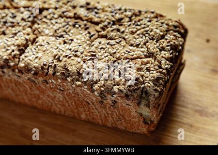 Pane rustico multigrano coperto da uno strato generoso di semi misti su una tavola di legno. Foto Stock