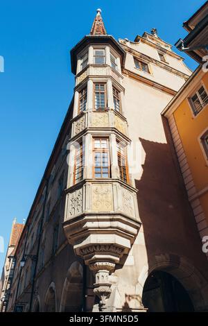 Finestra ad angolo storica dell'ex rettorato luterano con intagli in pietra a filigrana davanti a una tipica fila di case alsaziane, nel centro storico Foto Stock