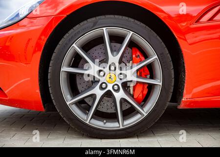 Vilnius, Lituania - 2026-06-06 - Ruota anteriore di una Ferrari California con disco freno forato a croce e ventilato, pinza freno rossa e logo Ferrari Foto Stock