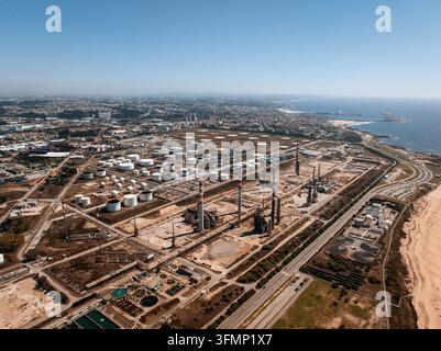 Vista aerea di una grande raffineria di petrolio con serbatoi di stoccaggio, torri di trattamento e tubazioni accanto alla costa atlantica in Portogallo, che mostra l'infrastruttura industriale Foto Stock