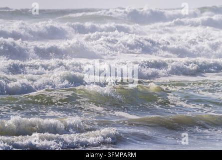 Agitate onde dell'Oceano Pacifico che si infrangono con una spessa schiuma bianca lungo la costa del Fort Stevens State Park in Oregon. Foto Stock