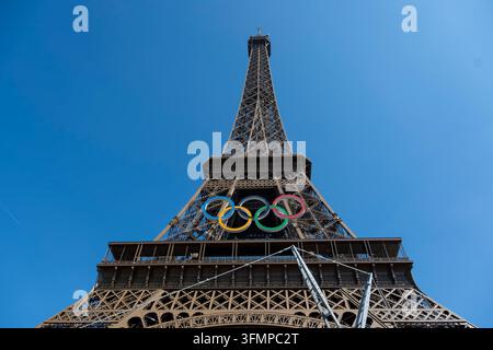Parigi, Francia – 7 giugno 2024: Ripresa a bassa angolazione della Torre Eiffel a Parigi decorata con i cinque anelli olimpici contro un cielo blu brillante, che celebra Foto Stock